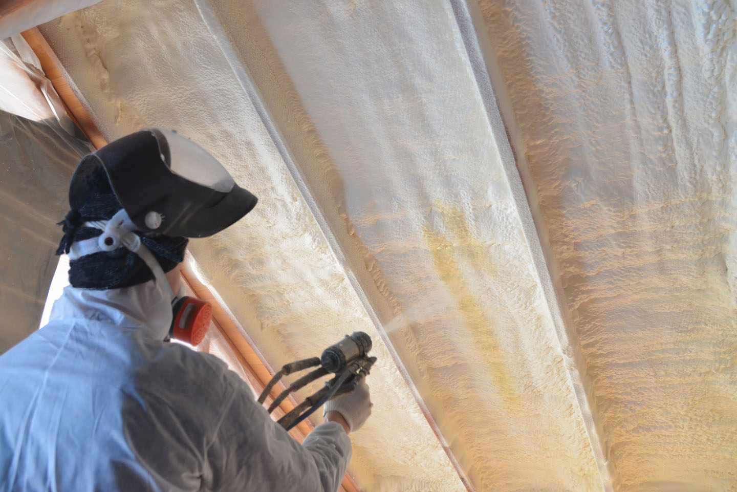 Insulation contractor sprays polyurethane spray foam on roof